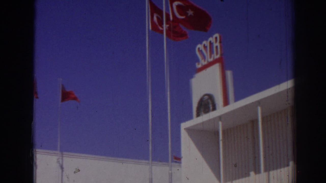 Turkish flags and SSCB sign above a white building against blue sky.