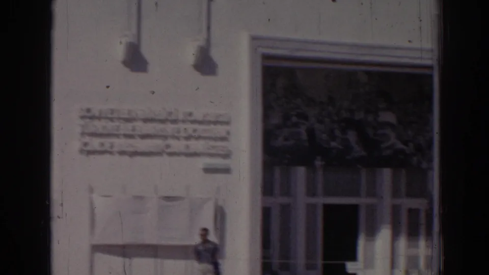 Final 1962 Izmir frame showing the inscription and entrance area of the white building, with flagpoles and film gate edges visible.