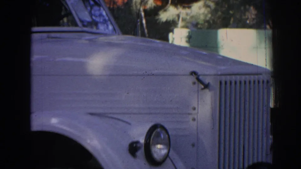 A tight 1962 Izmir home-movie view shows the older truck's front grille, headlamp, hood, and side panel in soft color.