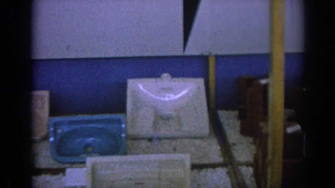White porcelain sink basin and blue basin on a textured surface against a blue and white wall.