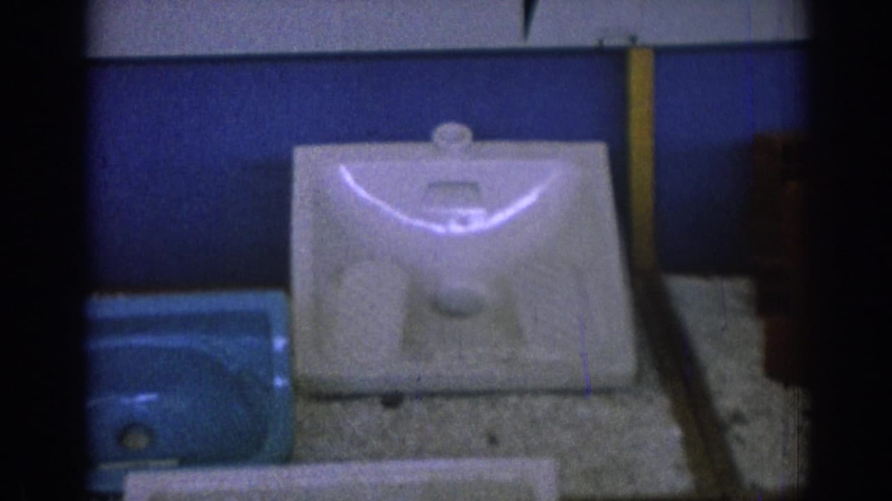 1962 Izmir frame with a white porcelain sink basin centered on a textured display surface and a blue basin partly visible at left.