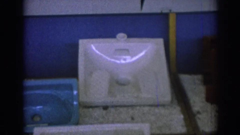1962 Izmir frame with a white porcelain sink basin centered on a textured display surface and a blue basin partly visible at left.