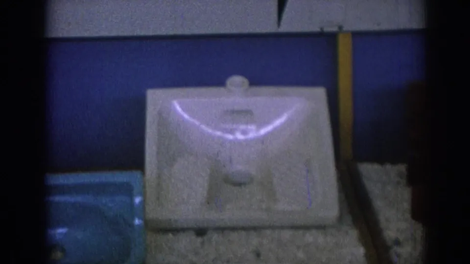 Final 1962 Izmir frame showing the white sink basin display, a partially visible blue basin, blue wall paneling, and dark 8mm frame borders.