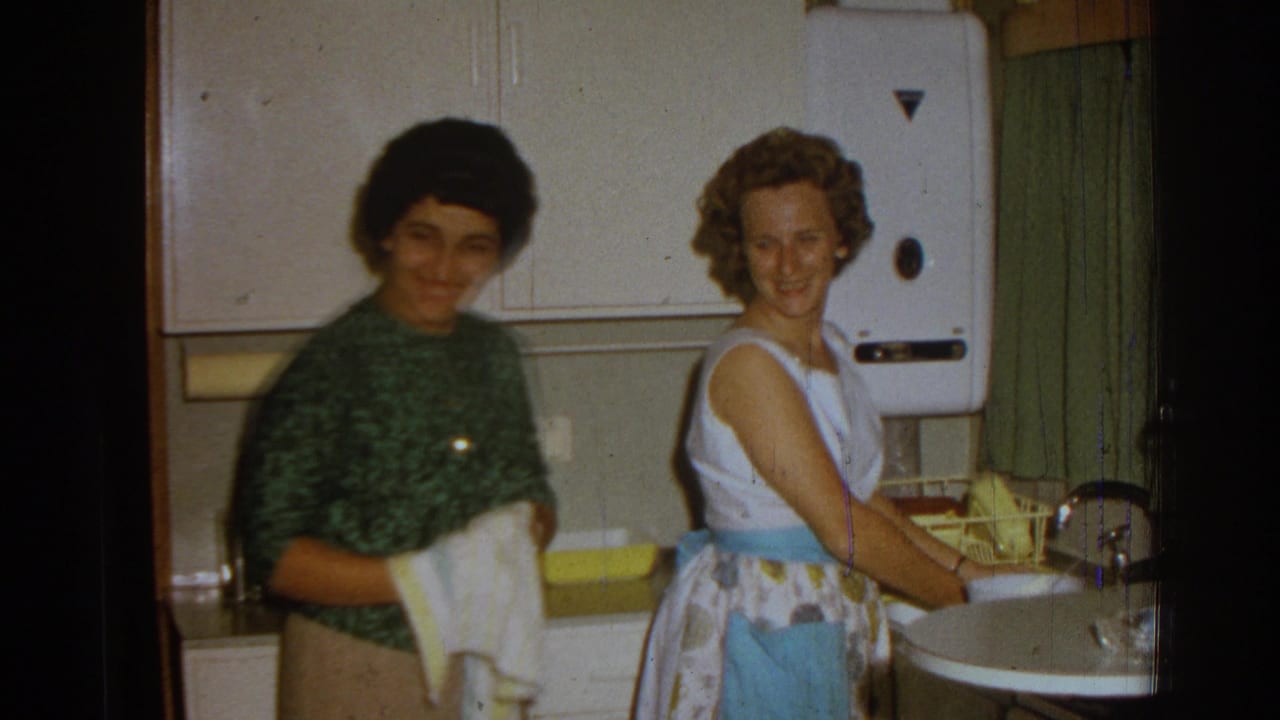 In a 1962 Izmir home interior, two women stand by a kitchen sink, one drying dishes while the other smiles toward the camera.