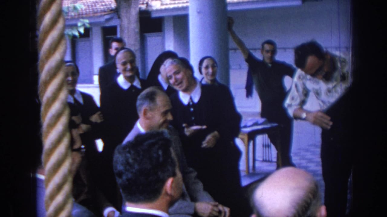 1962 Izmir convent courtyard scene with nuns in black habits, seated male visitors, and a man dancing or moving behind them.