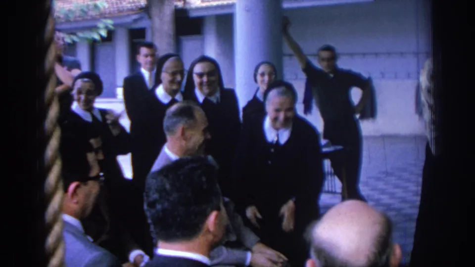 Nuns in a 1962 Izmir convent courtyard face seated male visitors, with columns and tiled paving visible behind them.