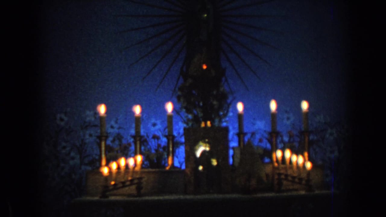 Central religious statue surrounded by lit candles in a dim church setting.