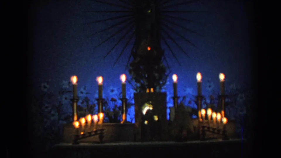 Candlelit 1962 Izmir church view with a central haloed statue, blue background glow, and ornate candleholders.
