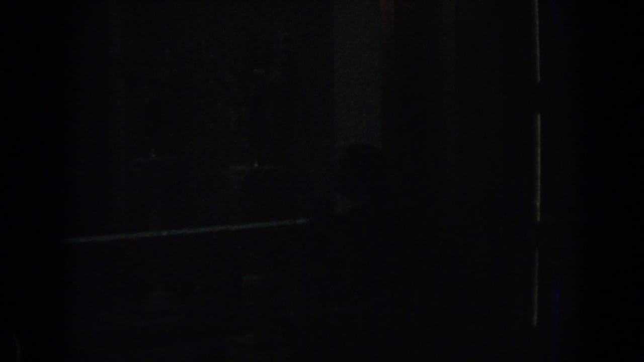 Underexposed 1962 Izmir home-movie frame showing a nearly black private interior with faint structural lines and possible shadow forms.