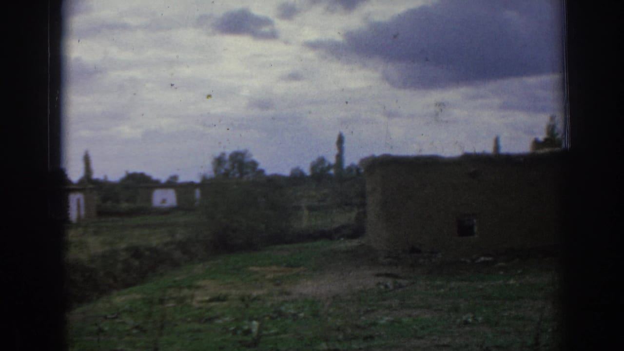 Rural earthen building near open ground under a cloudy sky.