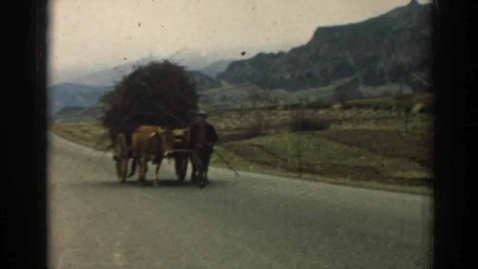 The horse-drawn cart continues along the mountain road in rural Turkey, with fields and hills visible through faded 8mm color.
