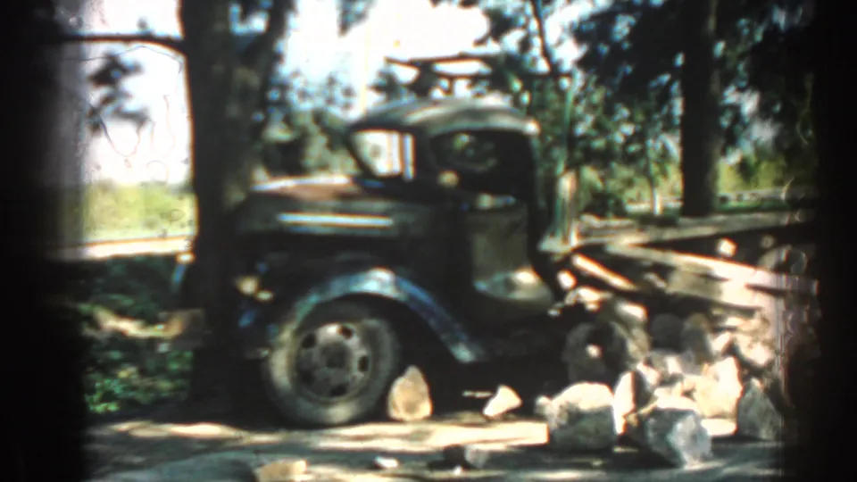 An older weathered truck sits under trees in the Izmir footage, with rocks and shade around the parked vehicle.