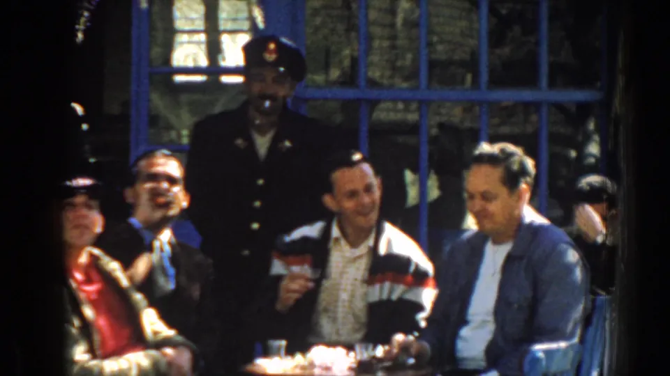 A final 1962 Izmir frame shows the group smiling and sitting with small glasses, framed by a tree trunk and blue window bars.