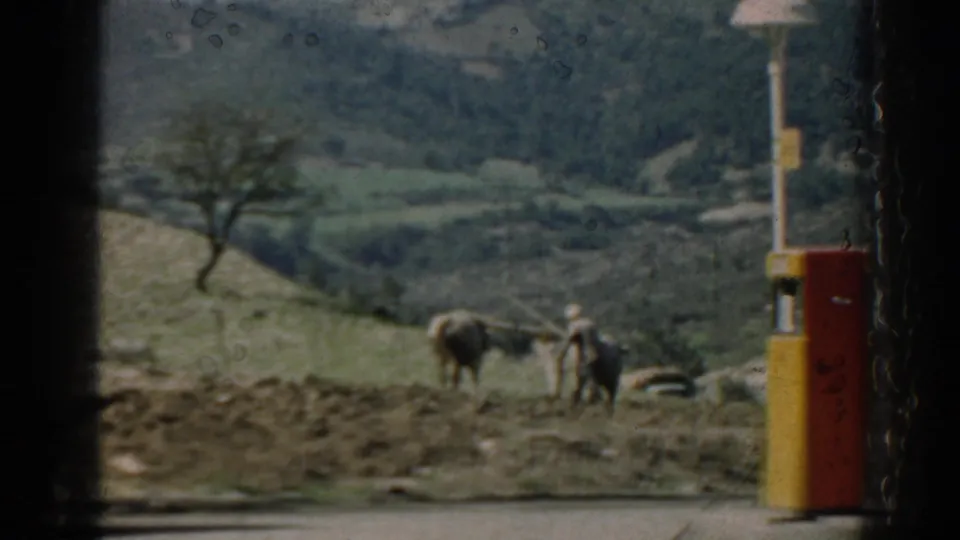 Later frame from the 1962 Izmir reel shows a rural roadside with hills, two people, livestock, and a painted roadside post.