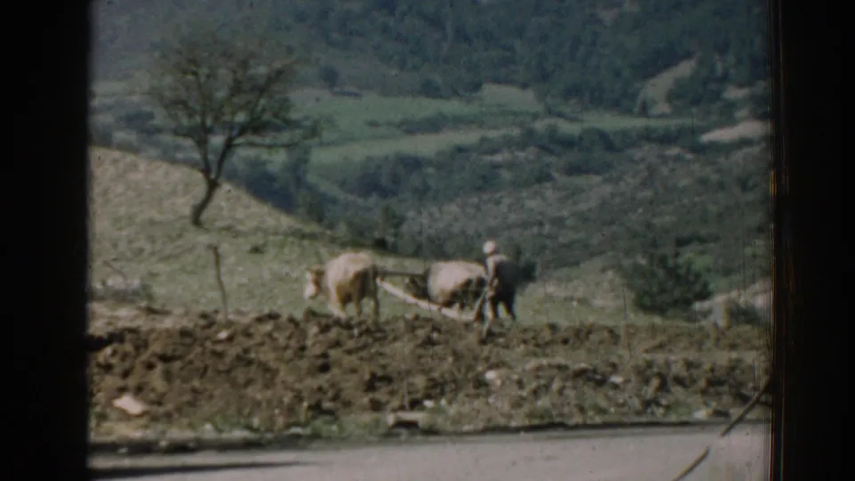 1962 Izmir frame showing a distant farmer guiding oxen with a plow against rolling rural farmland.