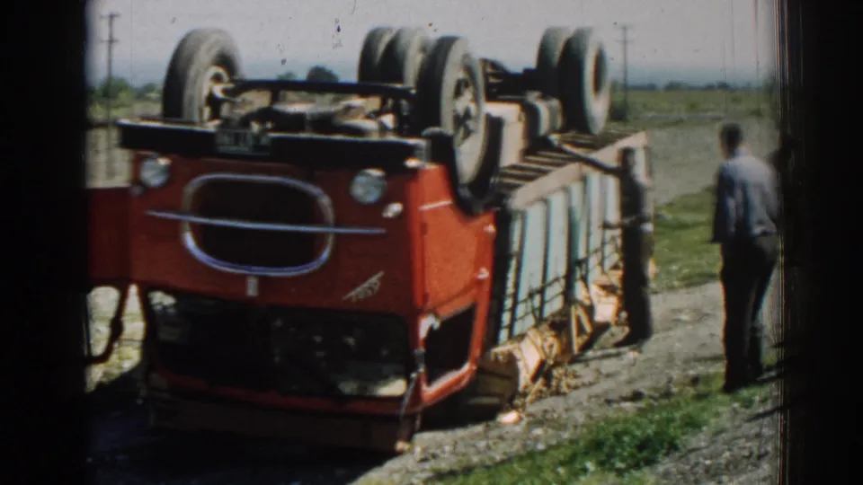 Izmir, Turkey, 1962 frame showing the overturned truck from near the cab, with men at the roadside and open fields beyond.