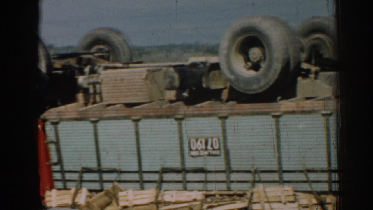 Close view of the overturned truck body with wheels above and a visible plate or marking.