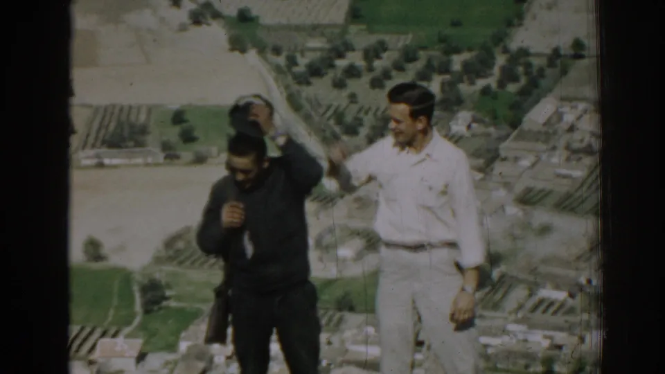 The uniformed man appears to lower his cap as the civilian stands nearby, overlooking rural land in 1962 Izmir.