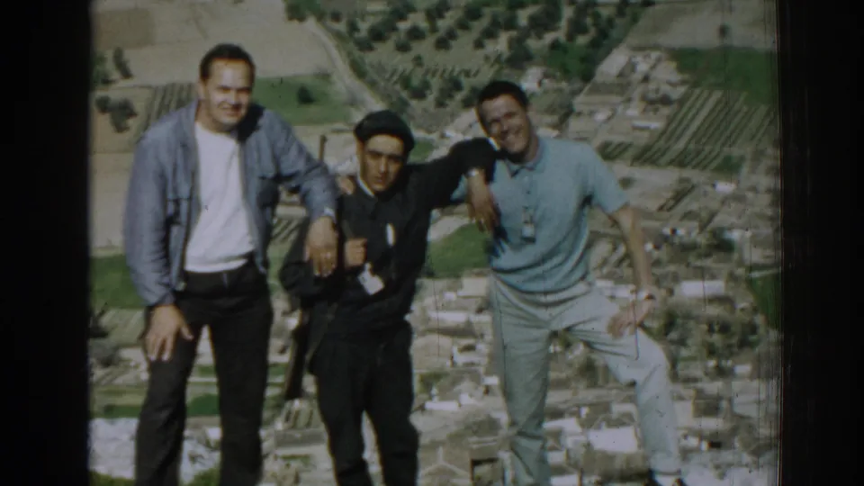 Three young men pose arm-in-arm on a hillside overlooking farmland in Izmir, Turkey, in 1962 home-movie footage.