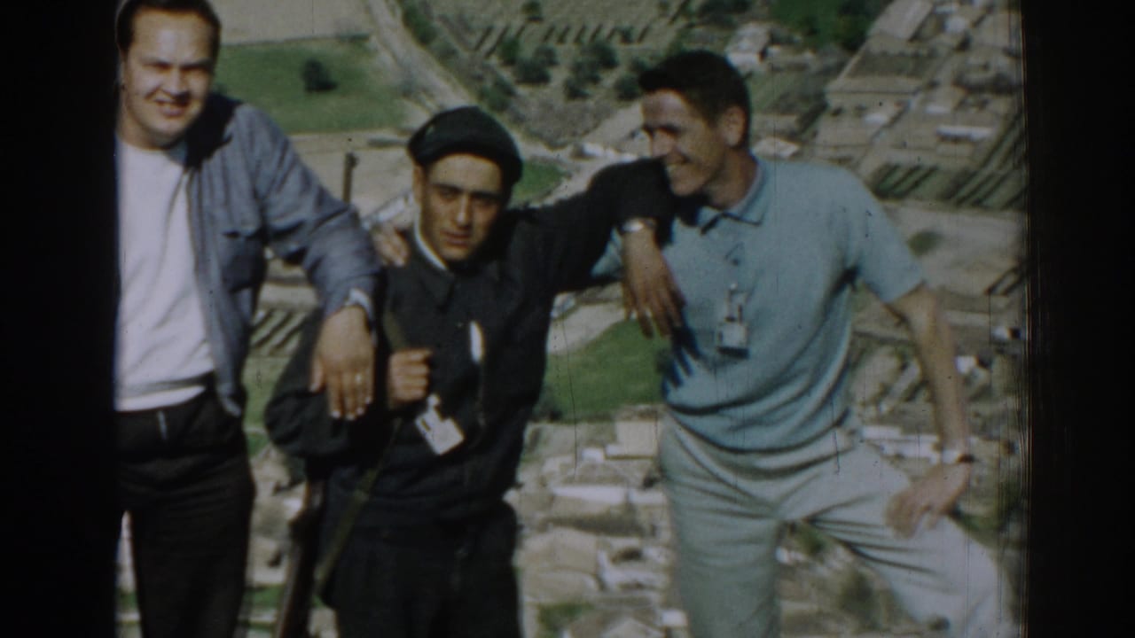 Three young men stand close together with farmland behind them.