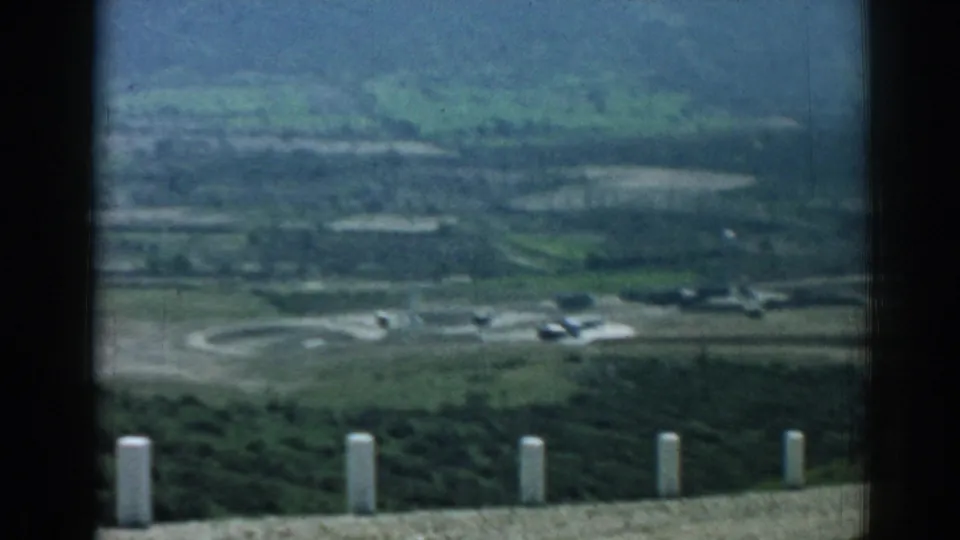 A soft 8mm valley view near Izmir shows roads, green fields, scattered structures, and distant aircraft-like forms.