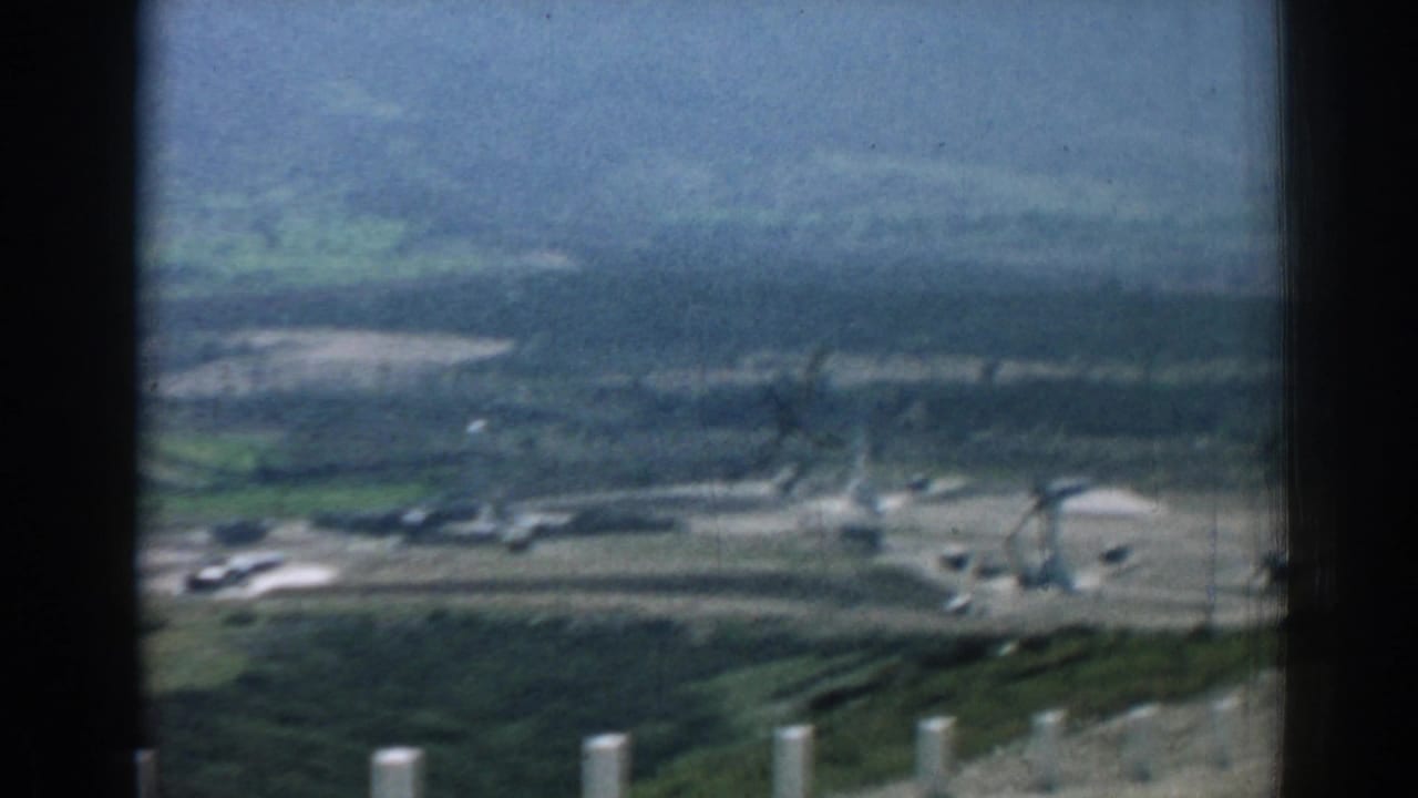 Hazy valley seen from a hillside with white posts in the foreground.