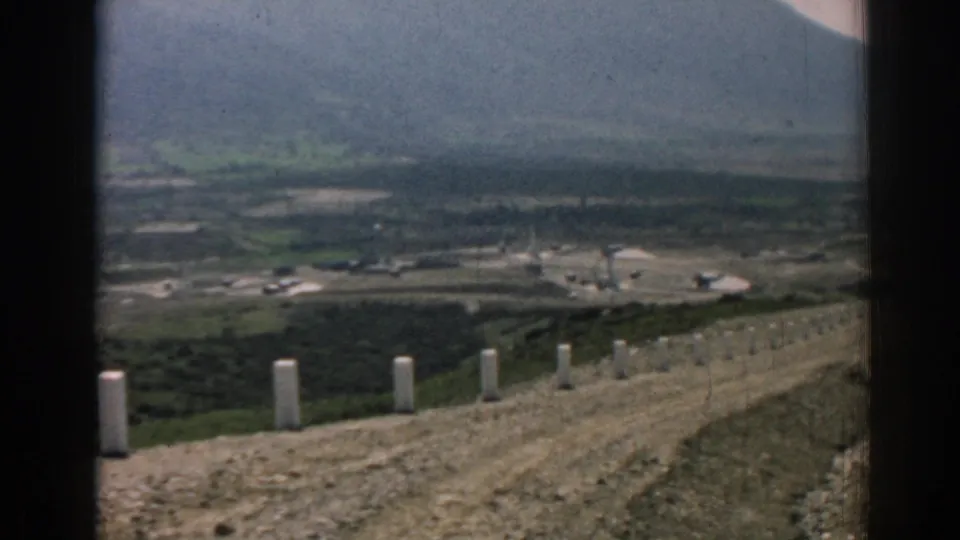 The moving 8mm view follows the unpaved ridge road in Izmir, Turkey, with roadside posts and a broad hazy valley below.