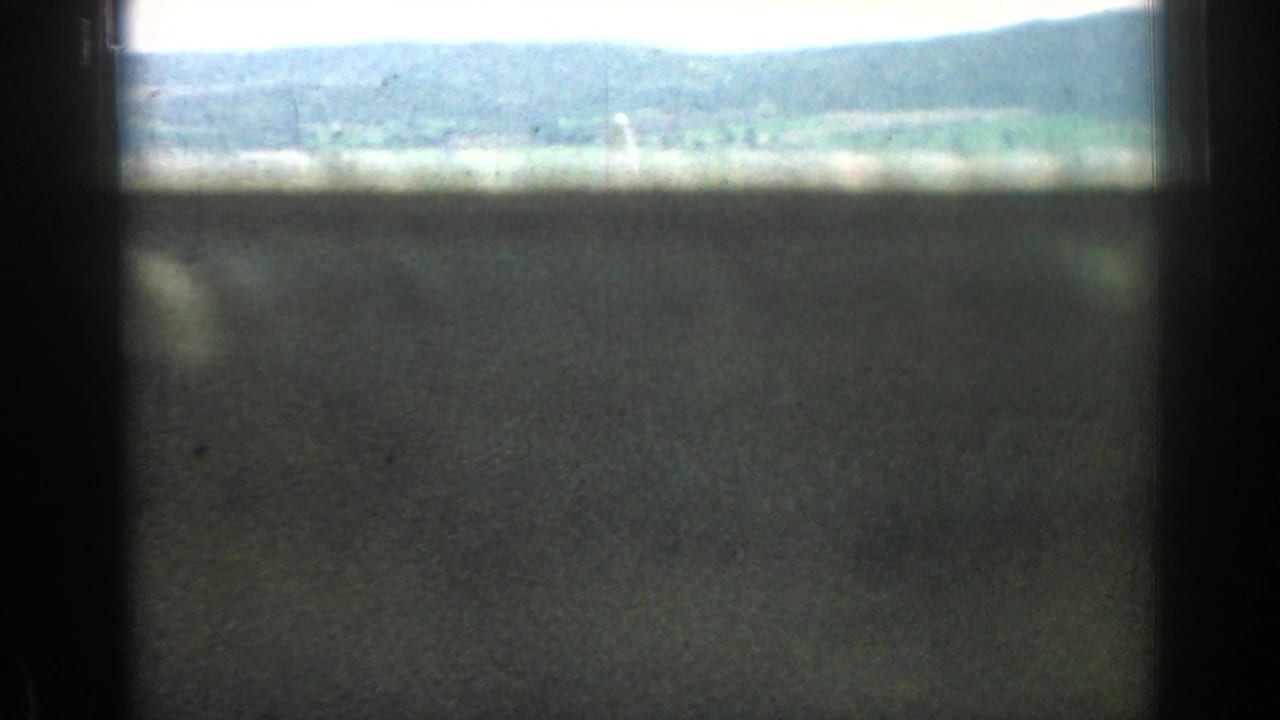 Obscured 1962 8mm view near Izmir, Turkey, looking past dark window framing toward hills and open landscape.