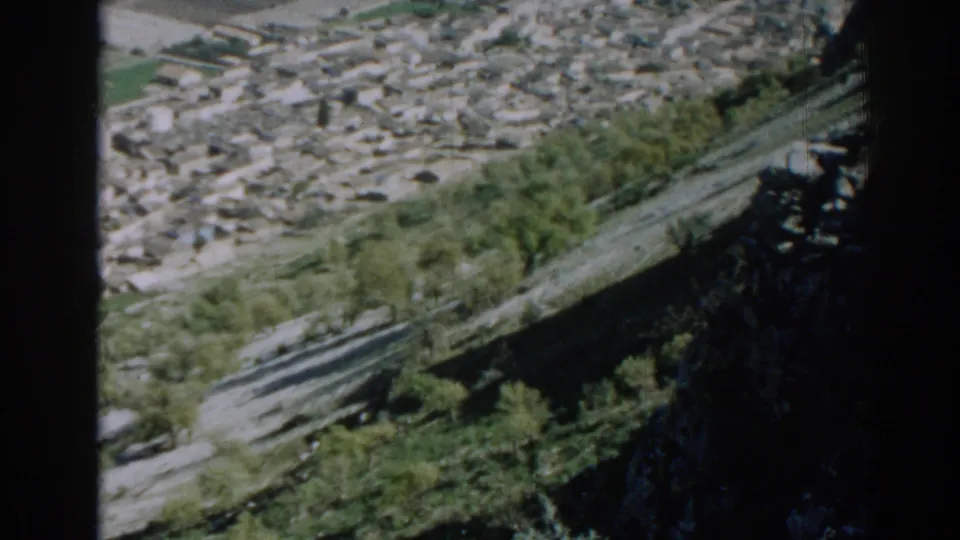 1962 Izmir frame with town buildings in the distance, hillside trees and road lines below, and dark film-edge shadowing.