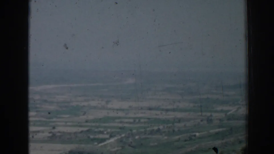 1962 Izmir, Turkey 8mm frame showing a broad hazy aerial landscape with fields, roads, and distant settlement.