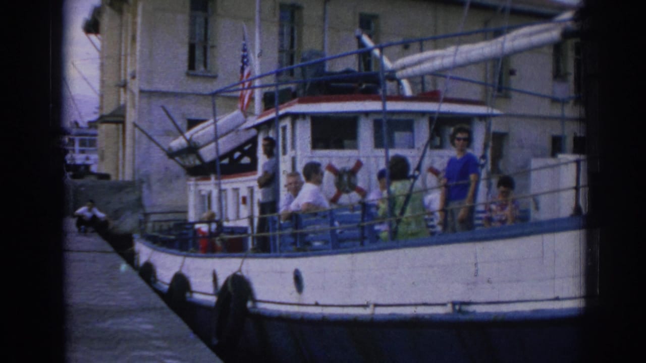 White and blue boat with passengers on deck and an American flag near the cabin.