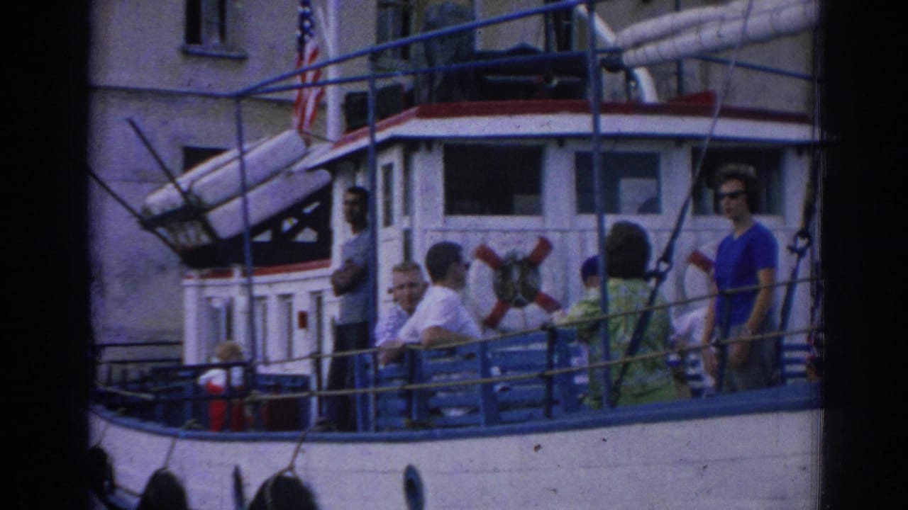 1962 Izmir frame with several passengers on a small boat deck, including a woman in blue sunglasses near a red life preserver.