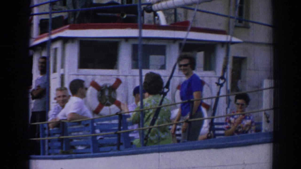 Closer 1962 Izmir home-movie view of passengers seated and standing on the boat deck, framed by ropes and cabin details.