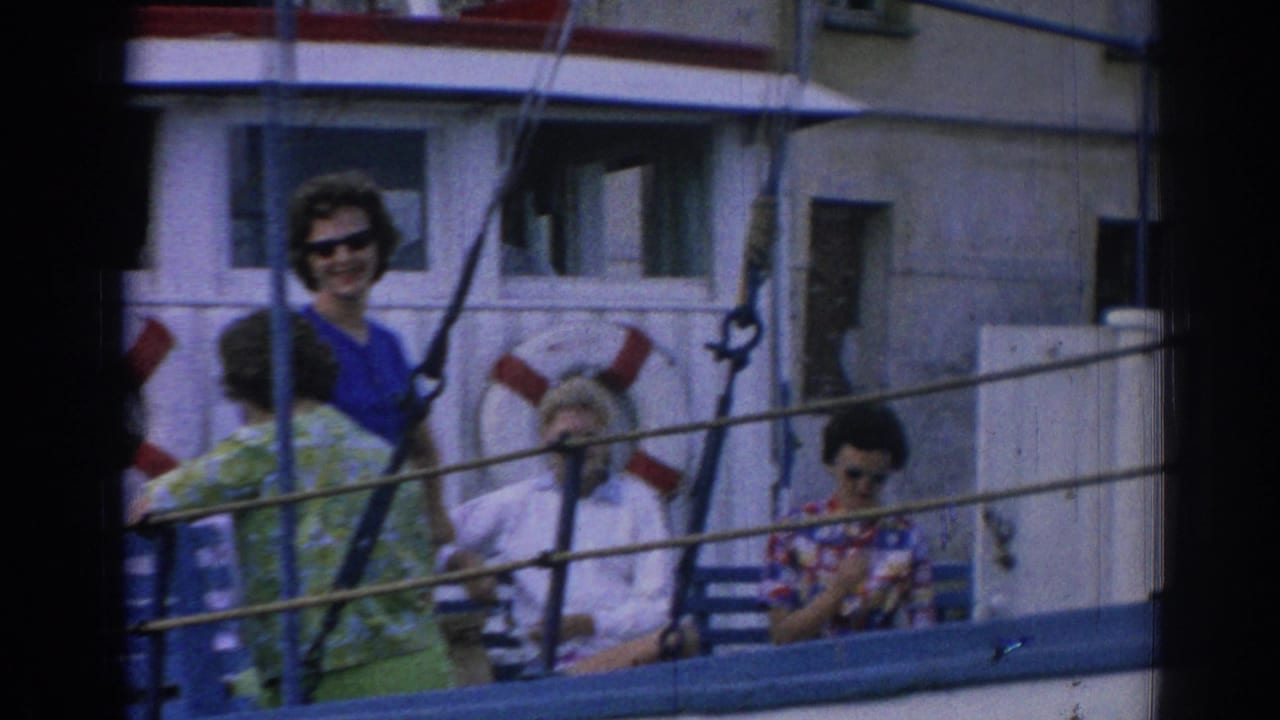 1962 Izmir boat-deck frame with a woman in blue sunglasses looking toward the camera and seated passengers near the cabin.