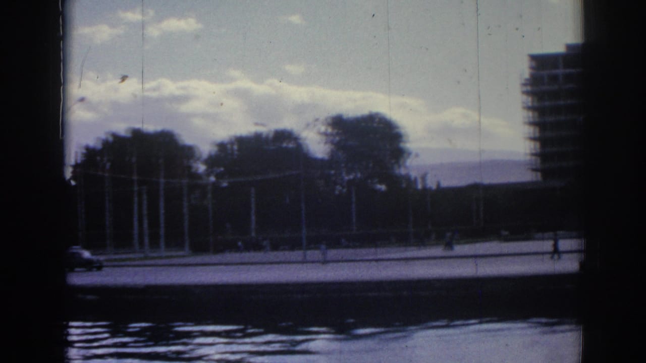 A wide 1962 Izmir waterfront view shows trees and promenade across the water, with a large building at the frame edge.