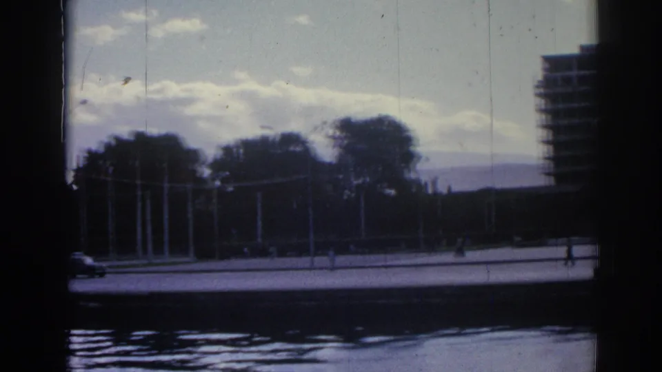 A wide 1962 Izmir waterfront view shows trees and promenade across the water, with a large building at the frame edge.