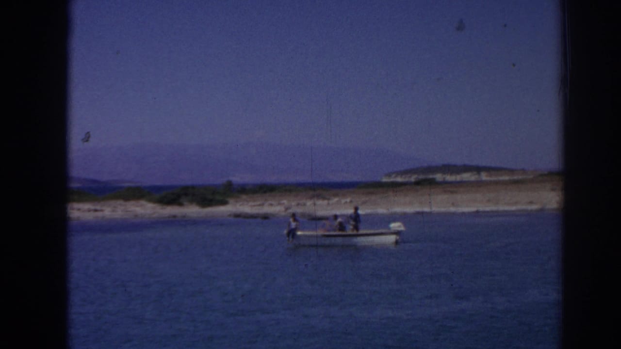 Small motorboat with passengers on calm water near a low shoreline and distant hills.