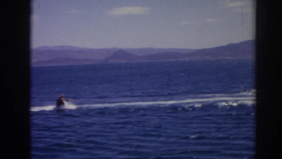 The skier appears farther from camera as the tow line and wake stretch across the blue sea near Izmir.