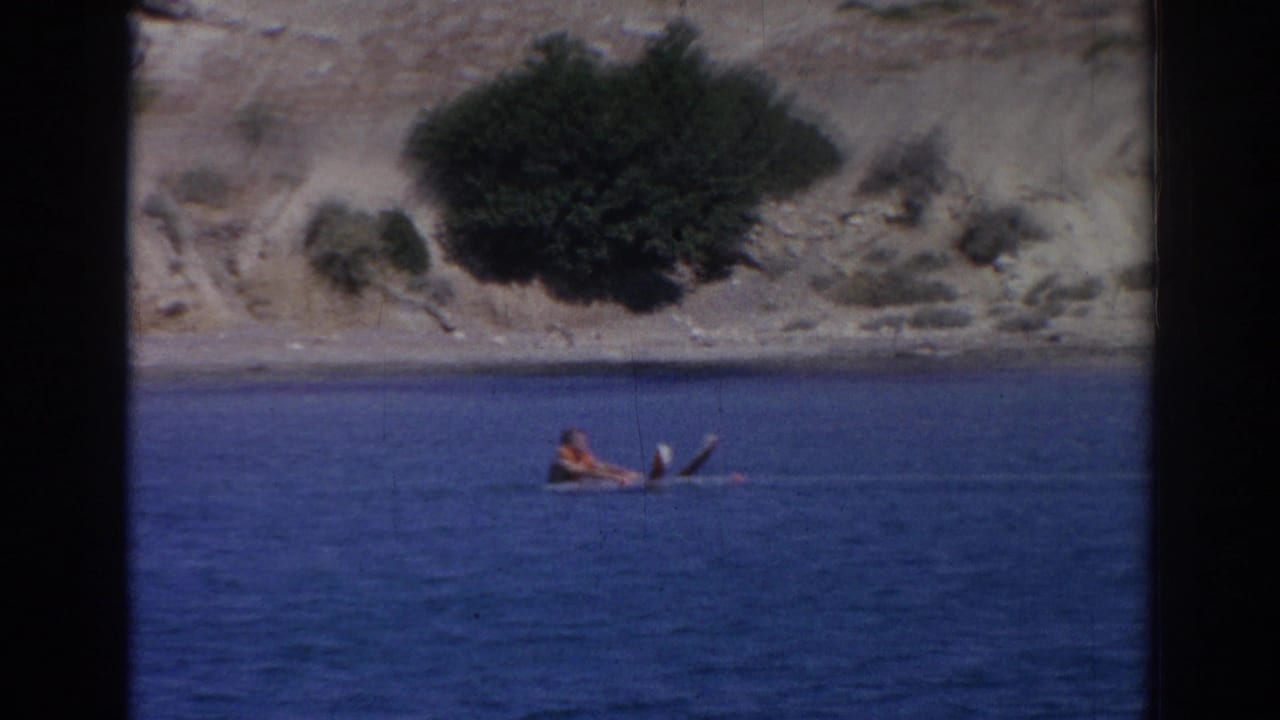 1962 Izmir frame of a distant water skier floating before the tow begins, with skis visible against calm blue water.