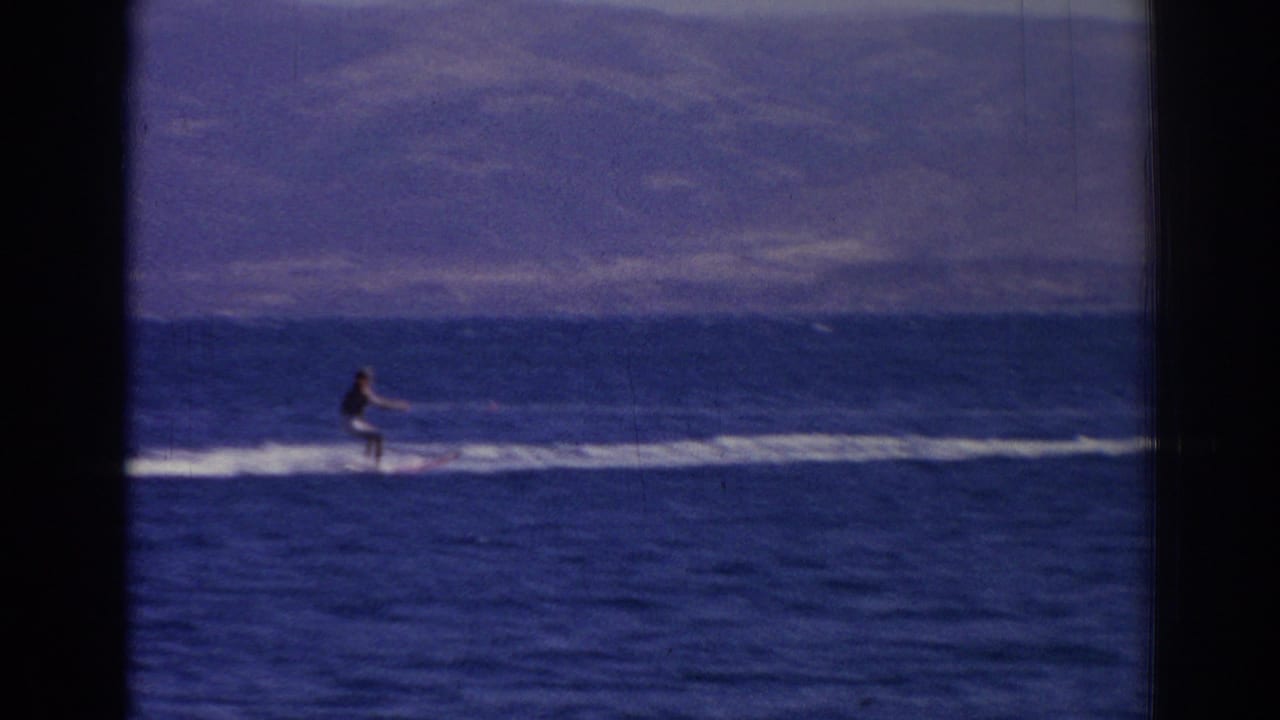 A distant watercraft rider crosses the sea near Izmir in 1962, framed by blue water, white wake, and soft mountain horizon.