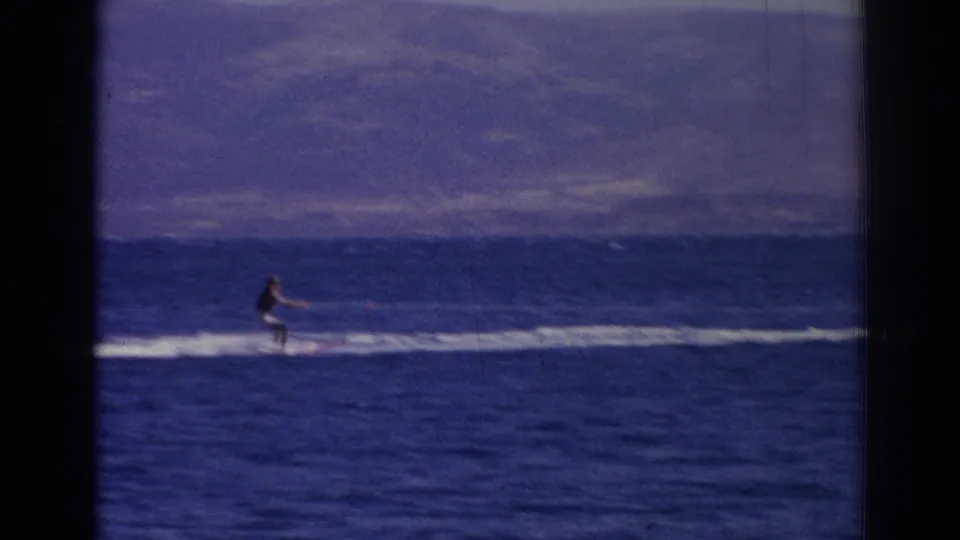 A distant watercraft rider crosses the sea near Izmir in 1962, framed by blue water, white wake, and soft mountain horizon.