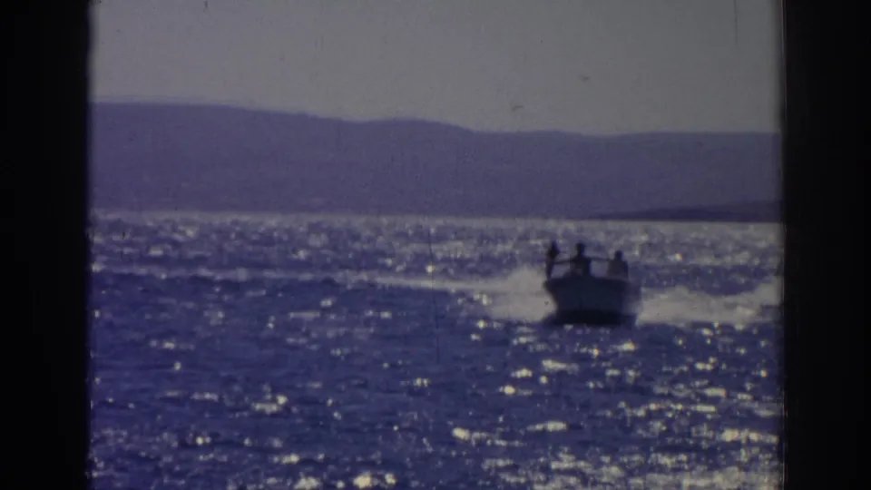 1962 Izmir, Turkey home-movie frame showing a motorboat crossing bright water with low hills on the horizon.