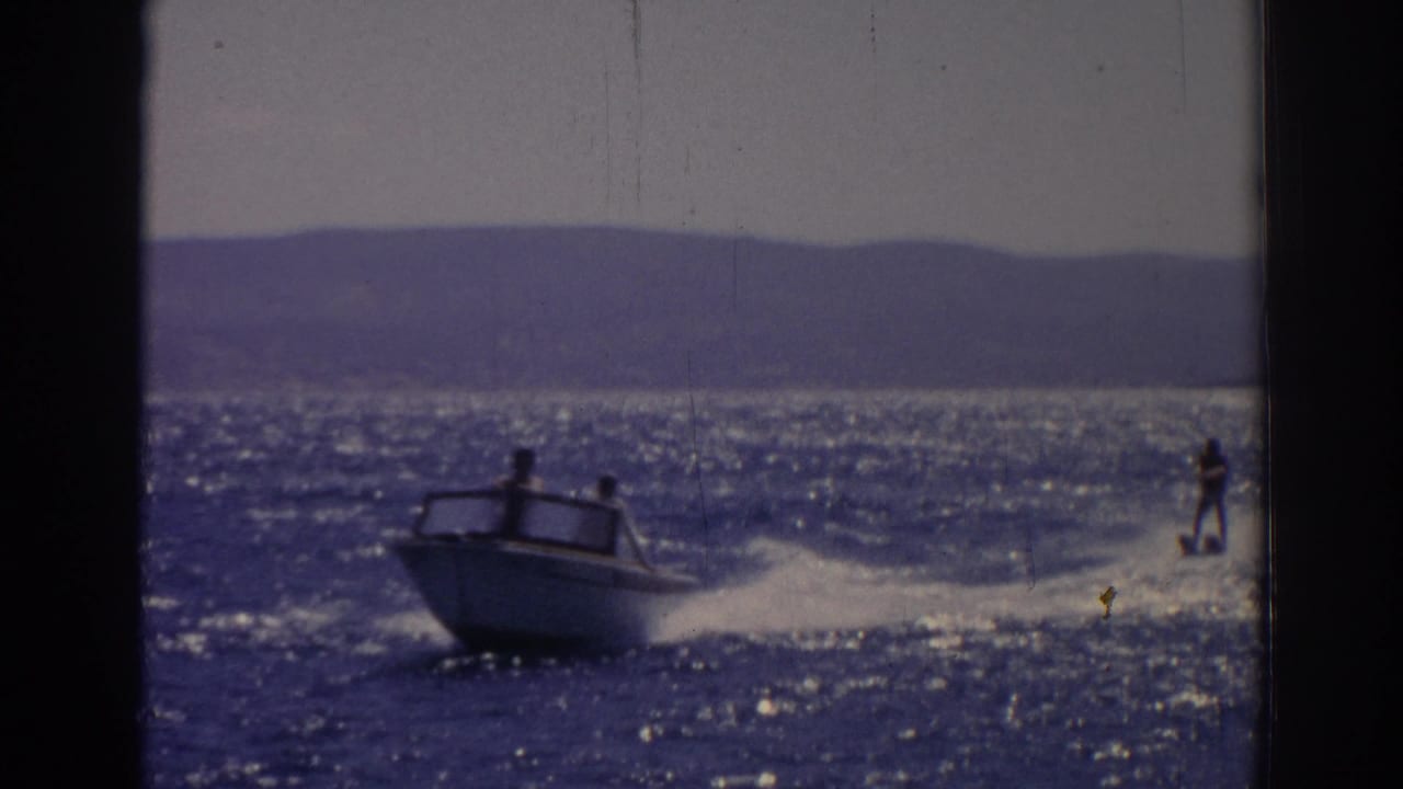 Speeding motorboat and water skier moving across choppy sunlit water.