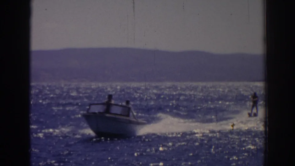 The boat continues across the water in this 1962 Izmir frame, leaving a white wake as the skier trails to the right.