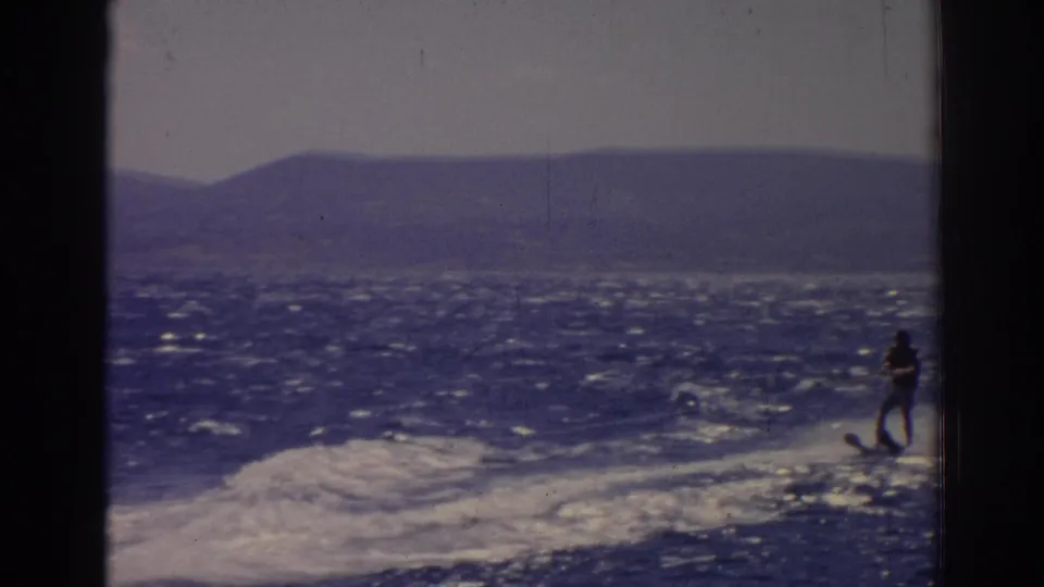 The final 1962 Izmir frame shows the skier near the right edge as the boat wake spreads across the sea below distant hills.