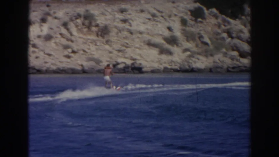 The rider appears smaller in frame as he crosses choppy blue water, backed by a pale rocky coast in Izmir, Turkey.