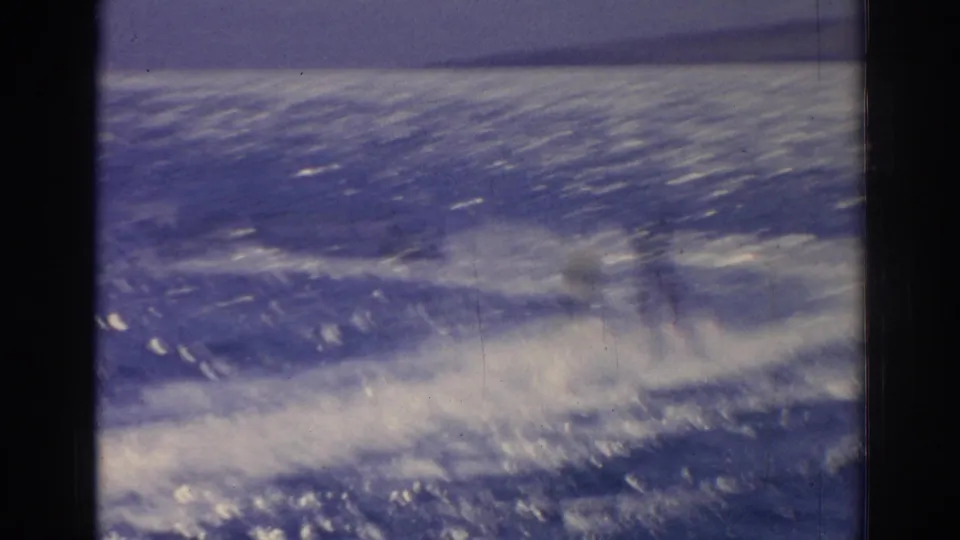 1962 Izmir home-movie frame showing bright sea spray, choppy blue water, and hazy coastal land beyond.
