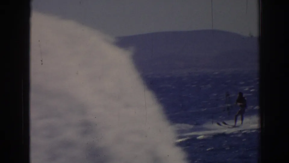 The water skier remains visible at right while a pale spray or foreground blur fills much of the 1962 Izmir home-movie frame.