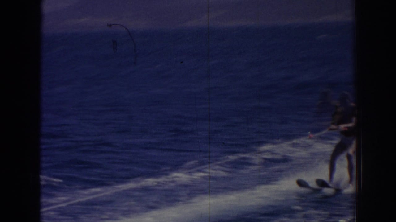 Water skier partly visible on a foamy wake across deep blue sea.