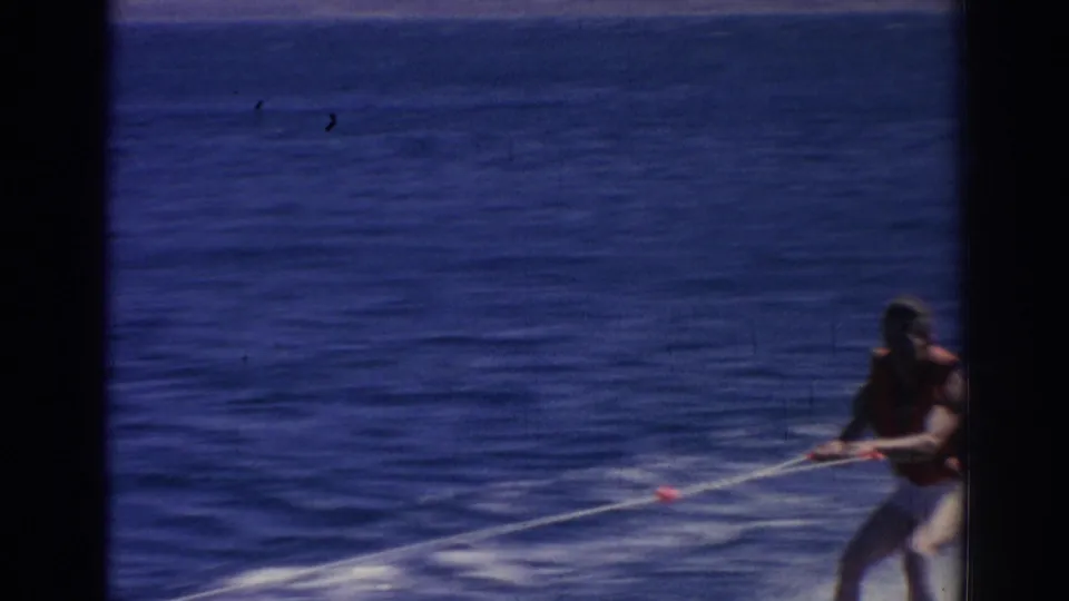 The skier, wearing a life vest, holds the tow rope as he crosses open water in the Izmir, Turkey home-movie clip.